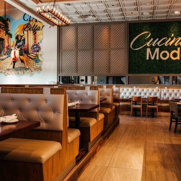 Modern Italian restaurant interior with booth seating, a mural, and a "Cucina Moderna" green wall.