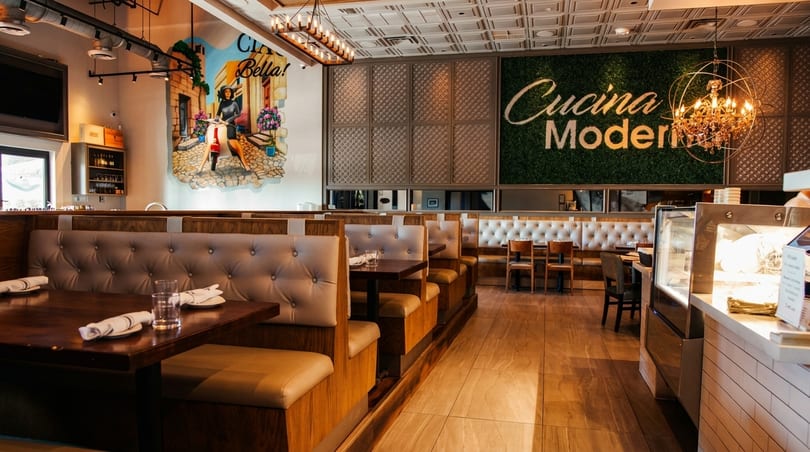 Modern Italian restaurant interior with booth seating, a mural, and a "Cucina Moderna" green wall.