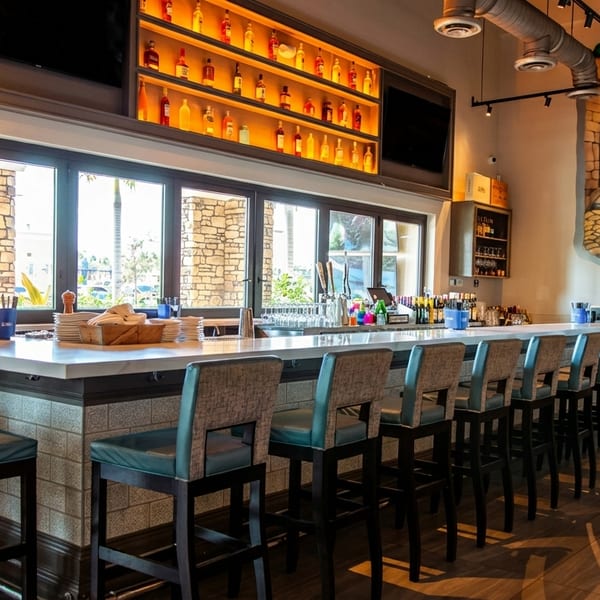 A long, well-lit bar with stools, a chalkboard menu, and a "Ciao Bella!" mural.